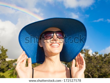 Portrait of woman enjoying the sun after the storm with a beautiful rainbow in the background.