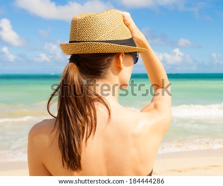 Beach vacation. Beautiful woman in sun hat and bikini enjoying beautiful beach, Hawaii, USA.