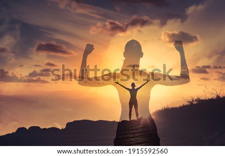 Silhouette of mental and physically strong woman standing on a mountain top. People, power, and strength concept.  