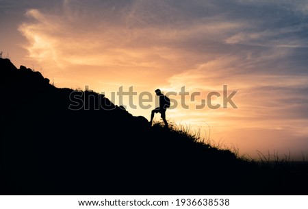 Male hiker climbing up the edge of mountain. Adventure and freedom concept. 