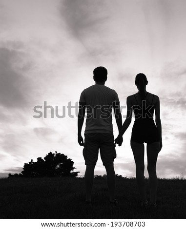 Silhouette of couple holding hands and enjoying sunset.