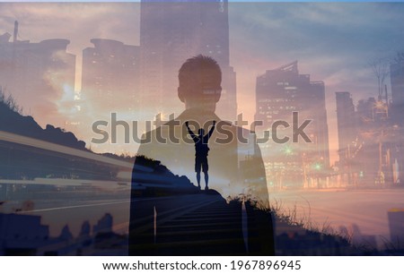 Young confident business man facing the city view. Man celebrating on a mountain top. People vision and inner strength, never giving up concept. 