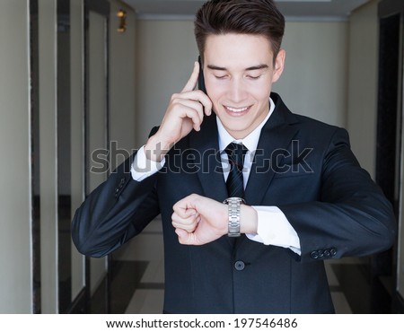 Businessman on the phone while checking the time on his wrist watch.