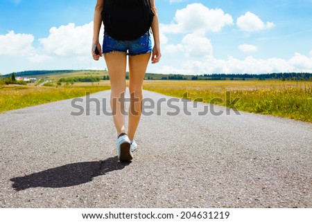 Woman walking down empty road on the country side. Adventure, sport and exercise.