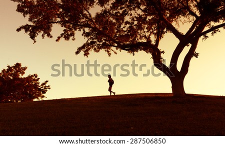 Woman backpacker walking trough a field at sunrise.