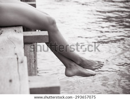 Woman relaxing her feet off a wooden dock.