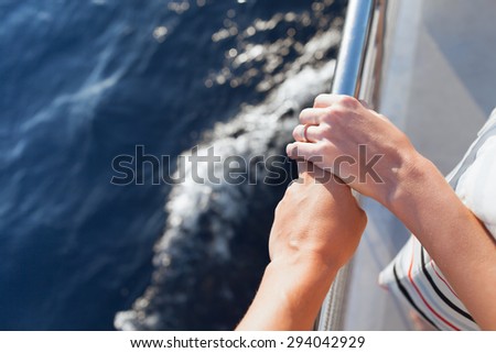 Couple on a sail boat holding hands.