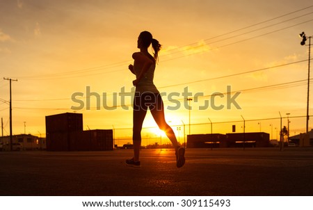 Silhouette of woman running in an industrial city setting