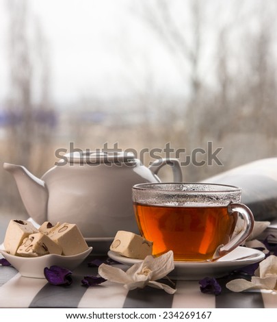 white teapot and  cup of tea with  deserts on the background view from the window