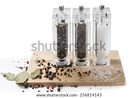 glass mill with pepper, salt and spices on a wooden board, isolated on white background.