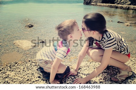 children brother and sister kiss on the beach. boy 5 years. girl 10 years old. toning vanilla effect.
