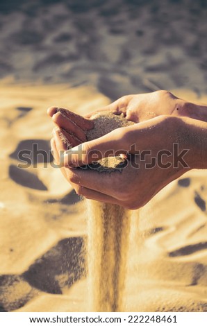 tinted image sand pours out of the female hands. horizontal