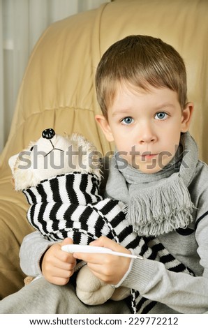 little boy measures the temperature of the toy dog. vertical