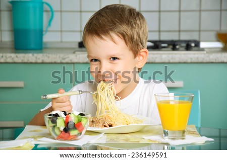 laughing boy eating spaghetti and holding the fork horizontal