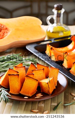 orange baked pumpkin, rosemary and olive oil on a kitchen table. vertical format