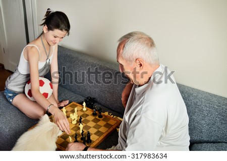 smiling granddaughter and grandpa playing chess horizontal