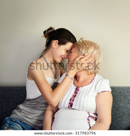 granddaughter hugging her grandmother and pressed against her face square format