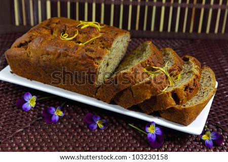 Homemade baked banana bread, sliced on wooden background, lemon zest garnish