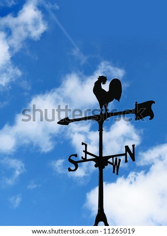 Wind cock direction on blue cloudy sky