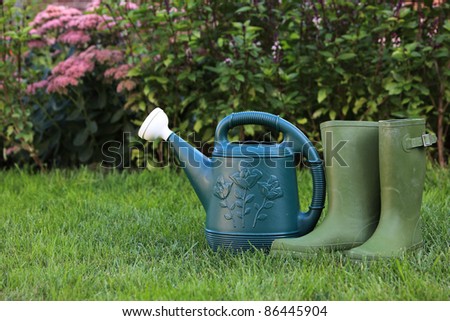 Watering can and rubber boots on the grass - Stock Image - Everypixel