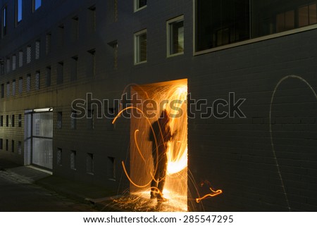 Person Reaching Into a Doorway in an Alleyway With Sparks Flying Out of it