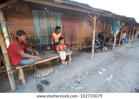 BALI, INDONESIA - APRIL 11: Unidentified children is sitting during his parents are working in a scavenging at the dump on April 11, 2012 on Bali. Bali daily produced 10,000 cubic meters of waste.