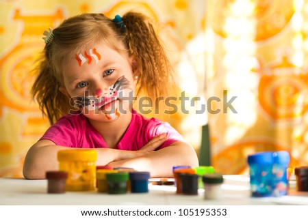 Little artist, drawing paint with paint of face.