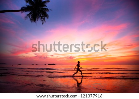 Beautiful sunset with silhouettes of girls on a beach jogger