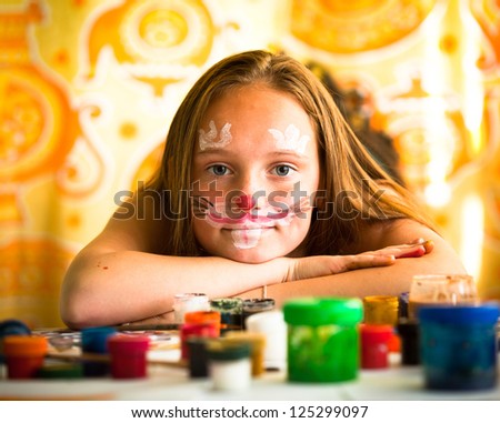 Little girl artist, drawing paint with paint of face.