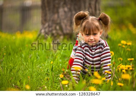 Lovely emotional five-year girl sitting in grass.
