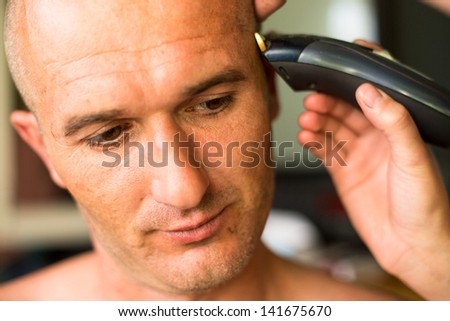Close-up: Hairdresser makes hairstyle bald man.