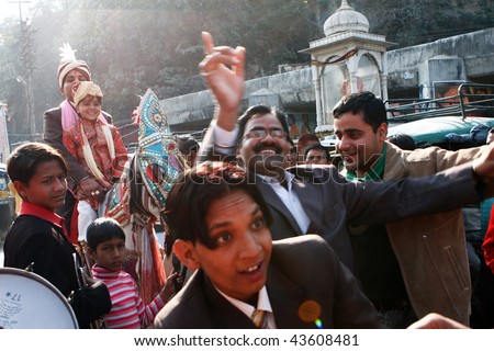 HARIDWAR, INDIA - JANUARY 14: The groom goes to bride, friends are dancing in front of the horse, to delay the moment of betrothal in traditional Indian wedding, January 14, 2009 in Haridwar, India.