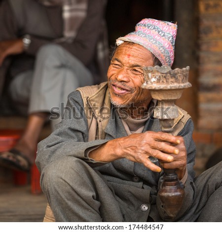 BHAKTAPUR, NEPAL - DEC 7, 2013: Portrait of unidentified Nepalese man smokes on the street. More 100 cultural groups have created an image Bhaktapur as Capital of Nepal Arts.