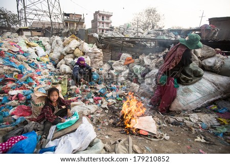 KATHMANDU, NEPAL - DEC 19, 2013: Unidentified child is sitting while her parents are working on dump. In Nepal annually die 50,000 children, in 60% of cases - malnutrition.