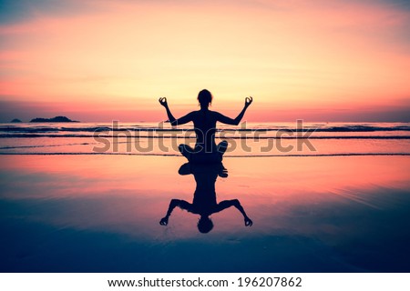 Yoga woman sitting on sea coast at sunset, picture-in-surreal colours.