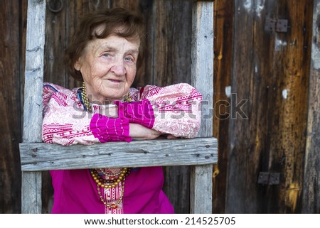 Portrait of old smiling woman in ethnic clothes in the village.