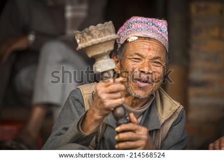 BHAKTAPUR, NEPAL - DEC 7, 2013: Portrait of unidentified Nepalese man smokes on the street. More 100 cultural groups have created an image Bhaktapur as Capital of Nepal Arts.