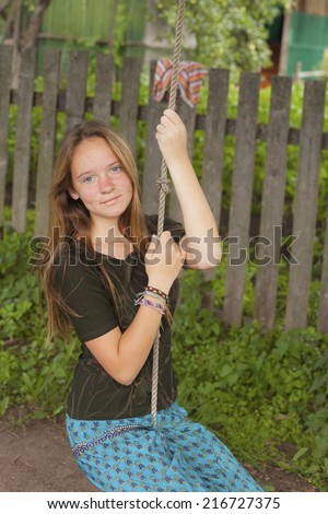 Teen girl swinging on a rope swing in the countryside.