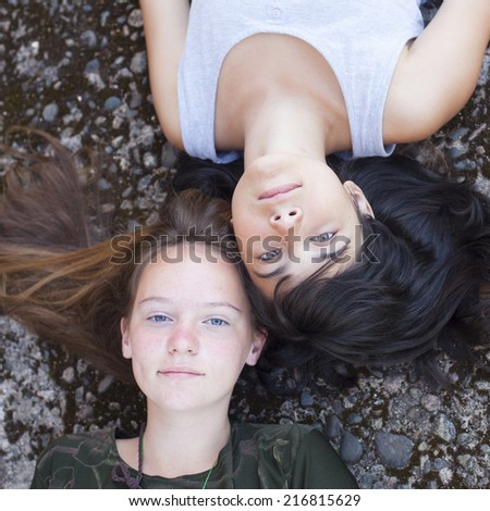 Two teen girl best friends lying on the rocks, top view.