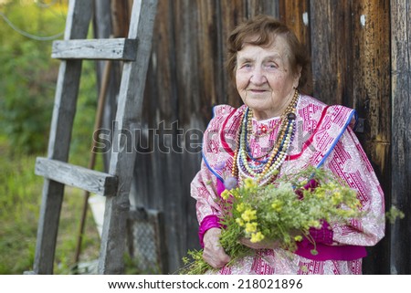 Old smiling woman, sitting on the street in the village.