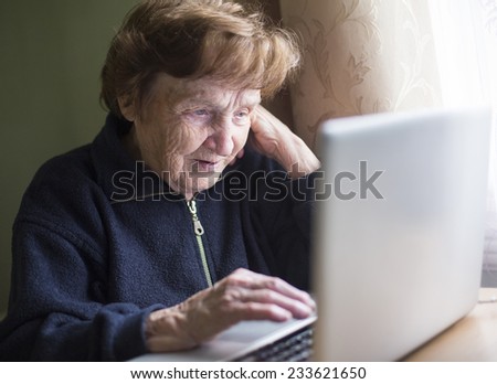 Elderly woman working on a laptop.