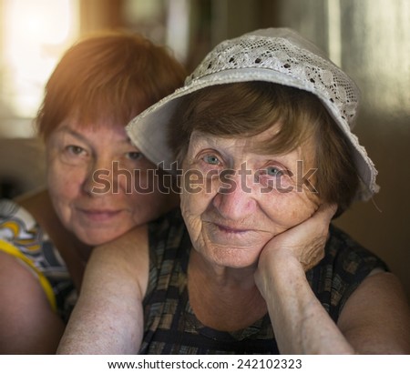 Portrait of old woman and hugging her daughter in the background, in the house.