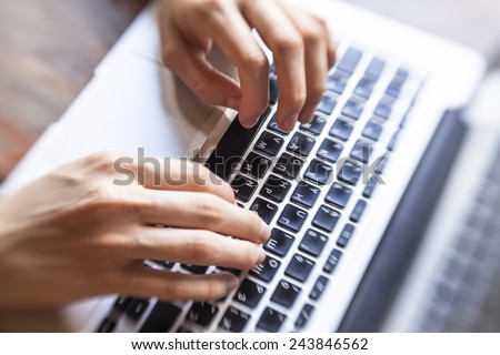 Female hands typing text on the keyboard, top view.