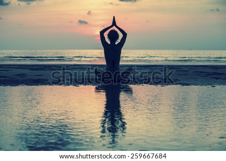Yoga, silhouette young woman on the beach at sunset, harmony of health.