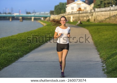 Young girl running on treadmill along river in the city.