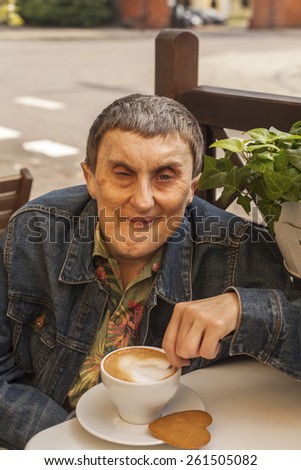 Portrait of elderly disabled man with cerebral palsy, at an outdoor cafe.