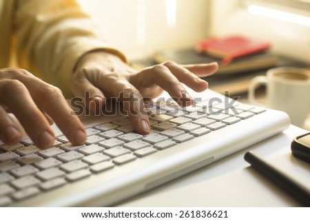 Women\'s fingers typing on laptop keyboard close-up.
