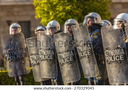 ATHENS, GREECE - APR 16, 2015: Riot police with their shields, take cover during a rally in front of the Athens University, which is under occupation by leftist protesters and anarchist groups.
