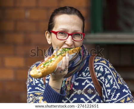 Young woman eating Polish fast-food a casserole (Zapiekanka)