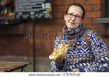 Woman eating Zapiekanka - Polish fast-food a casserole.
